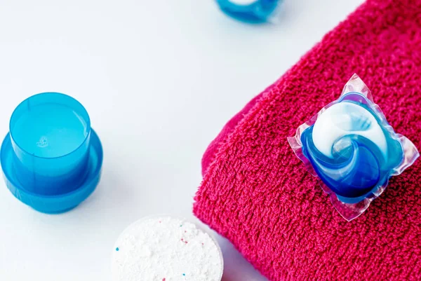 Kapseln mit Waschmittel und rosa Handtuch — Stockfoto