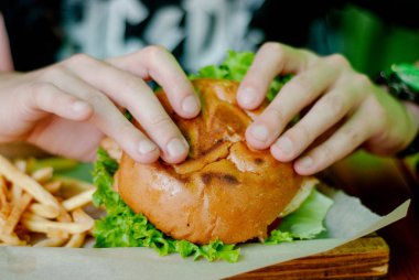 Bir restoranda hamburger yiyen adam, aç ve iyi bir ısırık içiyor. seçici odaklama