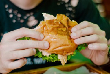 Bir restoranda hamburger yiyen adam, aç ve iyi bir ısırık içiyor. seçici odaklama