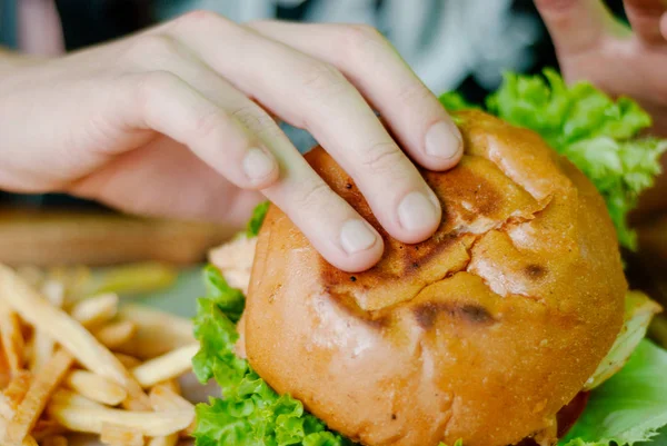 Man in een restaurant dat een hamburger eet, hij heeft honger en een goede hap. selectieve focus — Stockfoto