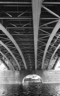 Bir nehir üzerinde metal bir köprünün altında. Siyah ve beyaz.