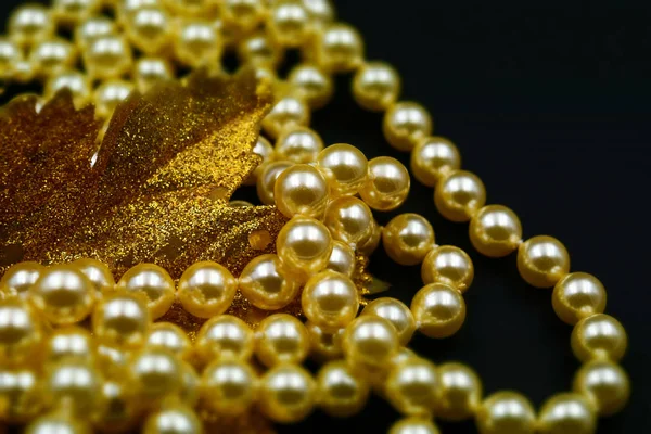 Pearls and glittering golden leaf with black background. Tilt-shift effect applied.