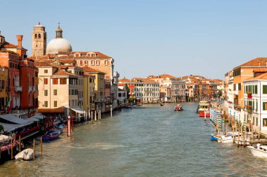 Venedik 'te, açık bir gökyüzünün altındaki canlı binalarla çevrili Gondol kanalı boyunca süzülüyor..