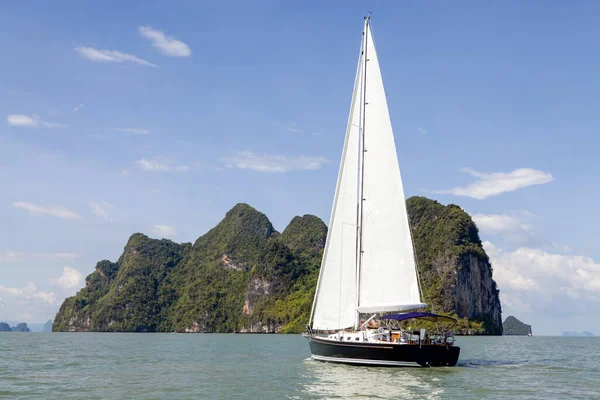 Phang Nga Körfezi 'nin turkuaz sularında ilerleyen bir yelkenli, parlak mavi gökyüzünün altındaki yüksek kireçtaşı kayalıklarıyla çevrili. Yelkenli maceraları için mükemmel koşullar..