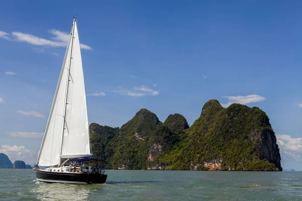 Phang Nga Körfezi 'nin turkuaz sularında ilerleyen bir yelkenli, parlak mavi gökyüzünün altındaki yüksek kireçtaşı kayalıklarıyla çevrili. Yelkenli maceraları için mükemmel koşullar..