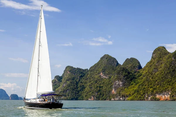 Phang Nga Körfezi 'nin turkuaz sularında ilerleyen bir yelkenli, parlak mavi gökyüzünün altındaki yüksek kireçtaşı kayalıklarıyla çevrili. Yelkenli maceraları için mükemmel koşullar..
