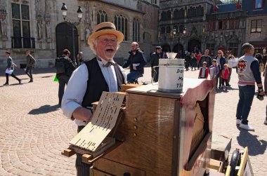 Bruges, Belçika-Mayıs 03, 2018: Street halk müziği sanatçısı (müzisyen) sokakta Milli takım elbiseli. Adam müzik üzerinde varil org çalan ve şarkı Burg meydanında