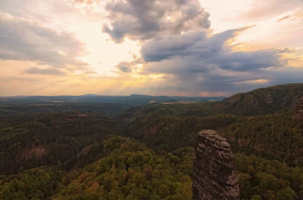 Panorama with typical rocky peaks under thunderstorms clouds. The sun\'s rays make their way through dense clouds. Bohemian Switzerland National Park. Czech Republic.