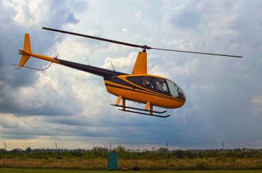 Küçük bir sarı helikopter çıkartıyor. Fırtına bulutları içinde belgili tanımlık geçmiş. Jitomir, Ukrayna küçük bir özel Havaalanı.