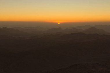 Scenic sunrise in the mountains. The sun comes out from the cloud. View from Mount Sinai (Mount Horeb, Gabal Musa, Moses Mount). Sinai Peninsula of Egypt. clipart