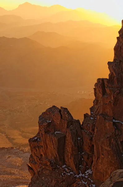 The sun rises behind the rock. Mysterious landscape of Mount Sinai (Mount Horeb, Gabal Musa, Moses Mount) during sunrise. Sinai Peninsula of Egypt. Pilgrimage place and famous touristic destination.