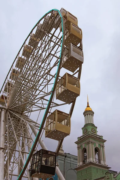 Ferris wheel in historical part of Kyiv. The bell tower of the Former Greek Monastery at the background. One of the most favorite squares among the locals. The Kontraktova Square. Kyiv, Ukraine