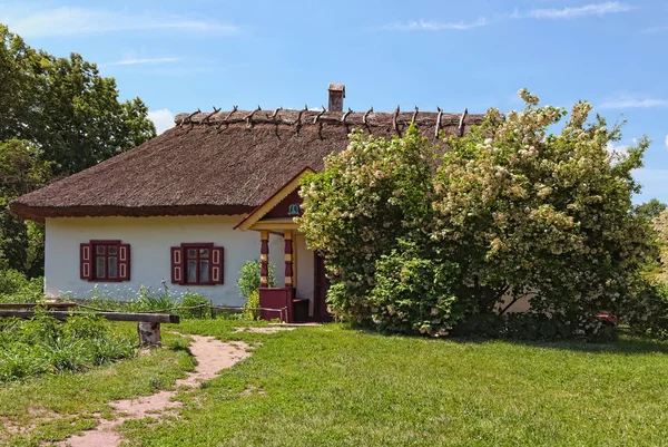 Superbe paysage d'une ancienne maison en argile avec un lit de fleurs au printemps ensoleillé. Musée Pereyaslav-Khmelnitsky d'architecture folklorique et de la vie du Moyen Naddnipryanshchyna. Ukraine — Photo