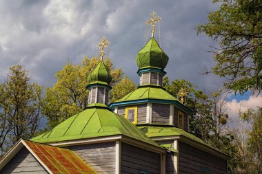 Bulutlu gökyüzüne karşı antik ahşap kazak kilisesinin manzara görünümü. Bahar fırtınasına birkaç dakika kala. Pereyaslav-Khmelnitsky Halk Mimarisi ve Orta Naddnipryanshchyna Yaşam Müzesi
