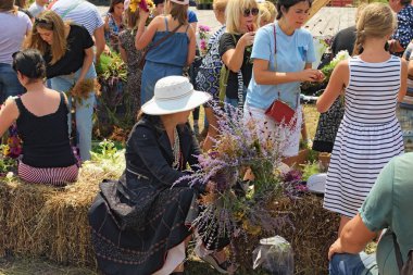 Kostivtsi, Ukrayna-13 Temmuz 2019: Bayan sadece onu çelenk yapma bitirdi. İnsanlar kır çiçeklerden çelenk dalıyor. Yaz konsepti. Harika Ukrayna geleneği. Berry Festivali Brusviana