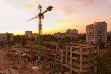 Yaz gün batımında büyük şehirde yüksek vinç ile şantiye. Eski binaların bulunduğu bir alanda yeni konut binasının inşaatı. Kiev, Ukrayna