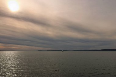 Balaton Gölü 'nün göz alıcı sonbahar manzarası. Bulutlu bir günde canlı bir gökyüzü. Güneş suya yansıyor. Balatonfold, Macaristan