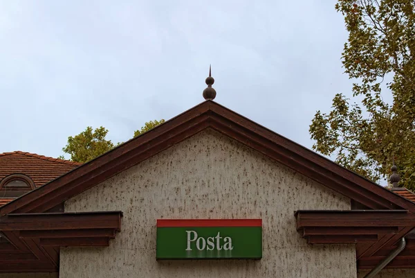 Parte superior de la fachada de la oficina de correos con un cartel POSTA (eng. oficina de correos) en Balatonfoldvar, Hungría. Nublado cielo otoñal al fondo. Vista de alta perspectiva — Foto de Stock