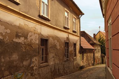 Narrow winding cobblestone road between ancient houses. Some parts of graffiti on the wall. Old part of the city Maribor, Slovenia. Autumn landscape  clipart