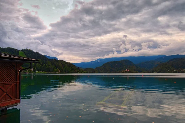 Wide angle landscape view of Bled Lake against cloudy sky. Clouds reflected in blue water. Beautiful mountains at the background. Famous touristic place and travel destination in Europe. Slovenia — Stock Photo, Image