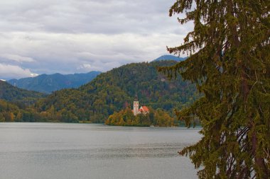 Bled Lake 'in sonbahar manzarası. Dağ sırasına karşı küçük bir adadaki Aziz Mary Hüküm Kilisesi 'nin görkemli manzarası. Bled Lake, Slovenya 'nın kuzeybatısındaki Yukarı Carniolan bölgesi.
