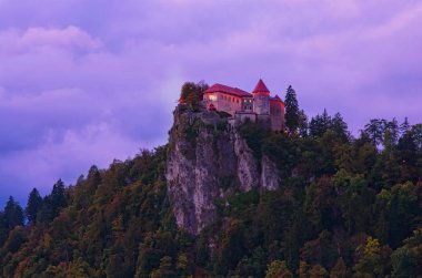 Canlı gökyüzüne karşı Kanlı Kale. Slovenya 'nın Bled kentinde, Bled Gölü' ne bakan bir uçurum üzerine inşa edilmiş güzel aydınlatılmış kale. Slovenya 'nın kuzeybatısındaki Yukarı Carniolan bölgesi