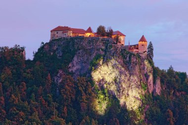 Gün batımında kayanın tepesindeki Bled Castle 'ın güzel manzara fotoğrafı. Slovenya 'da turistik bölge ve seyahat beldelerinin sonbahar manzarası 