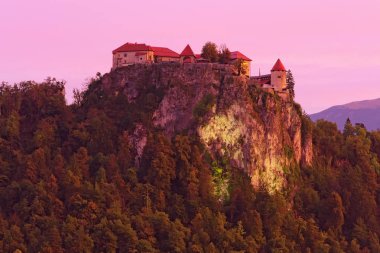 Gün doğarken kayanın tepesindeki Bled Castle 'ın resimli manzarası. Slovenya 'nın Bled kentinde, Bled Gölü' ne tepeden bakan bir uçurum üzerine inşa edilmiş bir ortaçağ kalesi. 