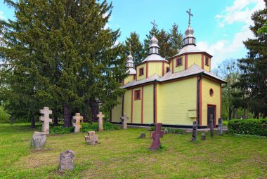 Mezarlığı ve eski taş haçları olan antik ahşap kilisenin geniş açılı manzarası. Antik Ukrayna 'nın tarihi binaları kavramı. Mimarlık Müzesi. 