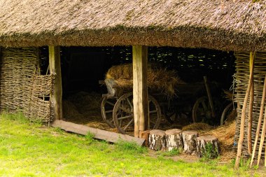 Hasır çatılı ve hasır duvarlı antik Ukrayna ambarının manzarası. Ahırda saman olan eski bir araba. Antik Ukrayna 'nın tarihi binaları kavramı.