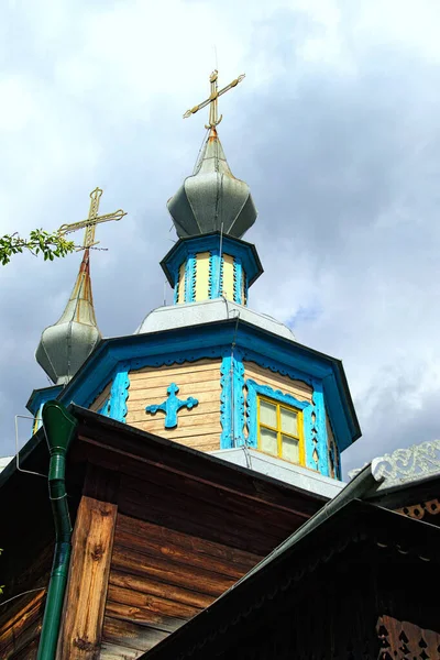 Close-up view of the dome of ancient wooden church against cloudy sky. Picturesque decorated facade by carved wooden platbands. Traditional view of the church in ancient Ukrainian villages. — Stock Image Close View Dome Ancient Wooden Church Cloudy Sky Picturesque Decorated Royalty Free Stock Photos