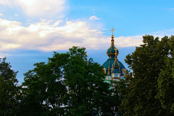 Ortaçağ St. Andrew Kilisesi 'nin tepesindeki beyaz bulutlu mavi gökyüzüne karşı şaşırtıcı doğa manzarası. Ağaç Yaprakları Sınırı. Doğal Çerçeve. Güneşli bir yaz günü. Kyiv, Ukrayna.
