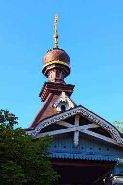Antik Ortodoks ahşap kilisesinin üst kısmına yakın çekim. Oyma ahşap platformlarla süslenmiş. Mavili gökyüzü arka planı. Hryshko Ulusal Botanik Bahçesi, Kyiv, Ukrayna.