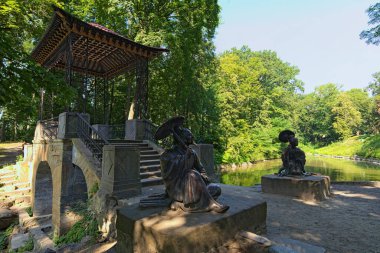 Bila Tserkva, Ukrayna-Temmuz 18.2020: Çinli bilge adam ve şemsiyeli genç kadın heykelleriyle ünlü Çin Köprüsü 'nün geniş açılı görüntüsü. Ünlü turistik yer ve romantik seyahat merkezi..