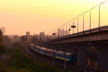Yeni Darnytskyi Köprüsü, Kyiv 'de Dnipro Nehri üzerinde birleşik bir yol ve demiryolu köprüsü. Demiryolu köprüsünün görkemli sabah manzarası ve geçen tren ve araçlı yol köprüsü..