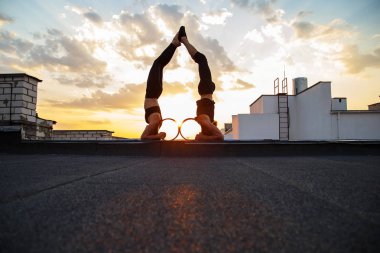 Bir erkek ve bir kadın buhar yogası yapıyorlar. Gün batımında çatıda yoga..