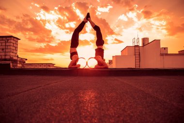 Bir erkek ve bir kadın buhar yogası yapıyorlar. Gün batımında çatıda yoga..