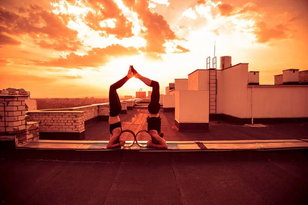 Bir erkek ve bir kadın buhar yogası yapıyorlar. Gün batımında çatıda yoga..
