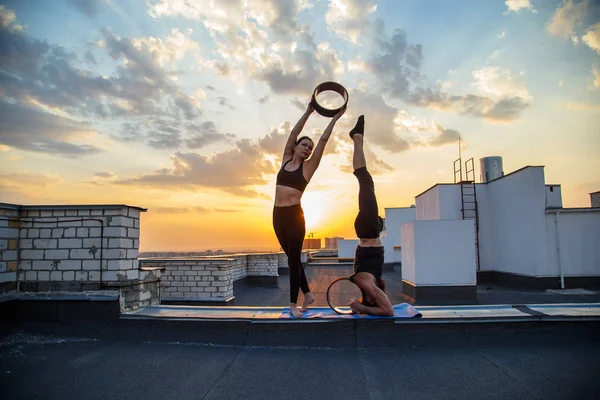 Bir erkek ve bir kadın buhar yogası yapıyorlar. Gün batımında çatıda yoga..