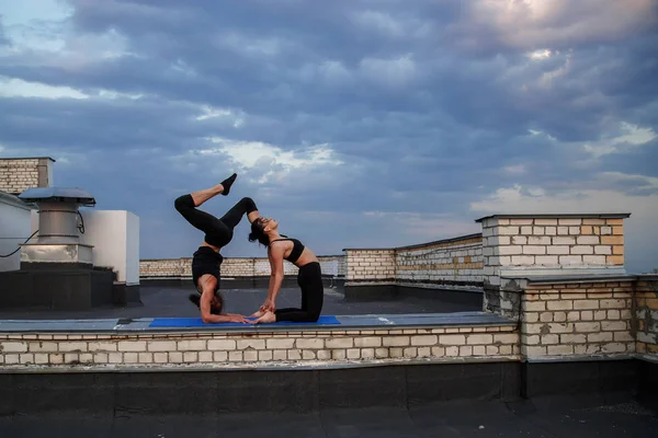 Bir erkek ve bir kadın buhar yogası yapıyorlar. Gün batımında çatıda yoga..