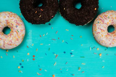 resim kırpılmış bir ahşap turkuaz arka plan üzerinde yarım daire içinde dört çörek, çikolata ve beyaz krema ile yalan