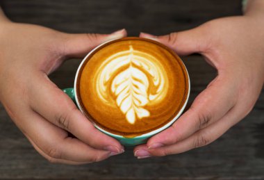 Ahşap arka plan bulanık üzerinde yeşil bir fincan cappuccino kahve erkeklerle el