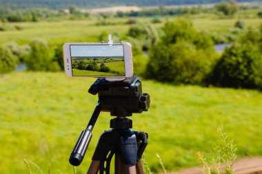Smartphone yaz manzara mavi gökyüzü ve çayır ile yakalama tripod üzerinde