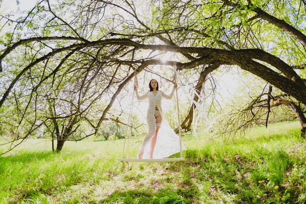 Verführerische junge Braut in weißen Dessous posiert auf einer Schaukel — Stockfoto