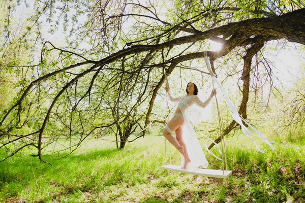 Bir kaç beyaz şeritler bir salıncak üzerinde poz çıplak uzun bacaklı seksi genç gelin