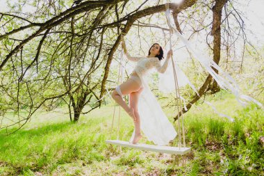 Bir kaç beyaz şeritler bir salıncak üzerinde poz çıplak uzun bacaklı seksi genç gelin