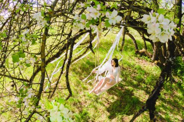 Baştan çıkarıcı poz beyaz bir salıncak üzerinde oturan genç seksi gelin