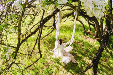 Baştan çıkarıcı poz beyaz bir salıncak üzerinde oturan genç seksi gelin