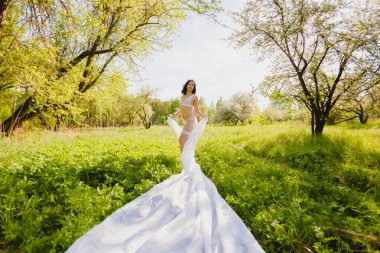 Genç Seksi esmer beyaz bez uzun bir parçası olan çiçek açan bir bahçe poz