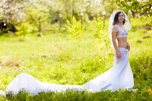 Jonge vrouw poseren in witte lingerie en rok van een groot stuk van het witte doek — Stockfoto